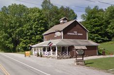 an old fashioned building on the side of a road in front of trees and grass