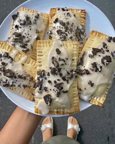 a person holding a plate with desserts on it