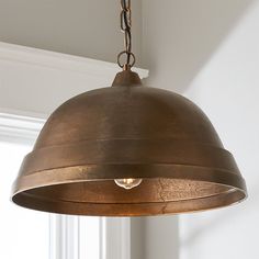 a light fixture hanging from the ceiling in a room with white walls and window sill