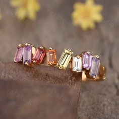 an assortment of colored stones on top of a piece of wood with flowers in the background