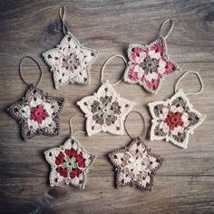 six crocheted ornaments are arranged on a wooden surface, each with red and white flowers