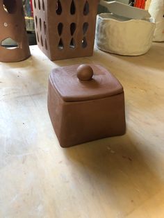 a brown box sitting on top of a wooden table next to other vases and containers