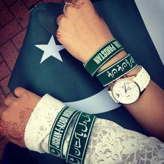 two people with wristbands on their wrists next to a pakistan flag