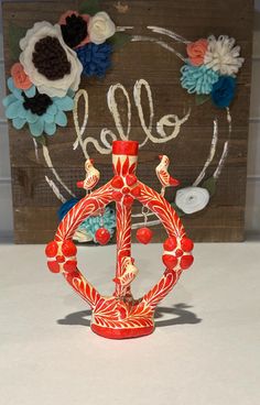 a red and white vase sitting on top of a table next to a wooden sign