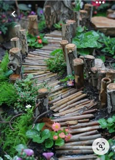 a wooden path made out of logs with flowers and greenery around it in the garden