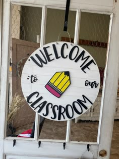 a welcome to our classroom sign hanging from the side of a door with an open window