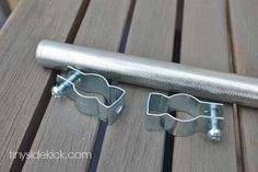 two pieces of metal sitting on top of a wooden table next to a pipe clamp