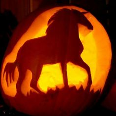 a carved pumpkin with a silhouette of a horse on it's front and side