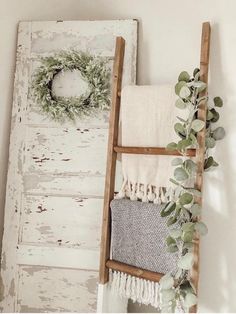 an old ladder is used as a towel rack for towels and wreaths on the wall