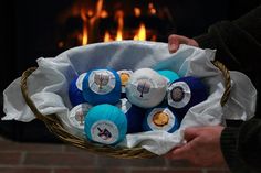 a person holding a basket filled with blue and white items in front of a fire place