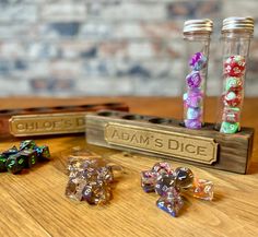 some dice are sitting on a table next to two glass bottles and one is filled with colored dice