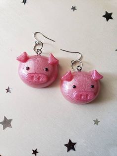 the pink pig earrings are hanging from silver earwires on a white background with stars