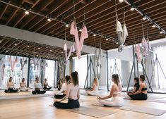 a group of people sitting on top of yoga mats in a room filled with windows