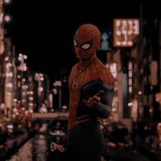 a spider - man standing in the middle of a city at night with his arms crossed