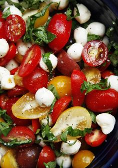 a salad with tomatoes, mozzarella and other toppings in a black bowl