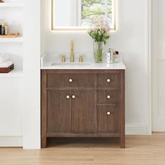 a bathroom vanity with a mirror above it and flowers in the vase next to it