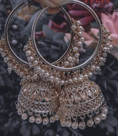 a pair of gold toned hoop earrings with pearls hanging from the middle, on a black background