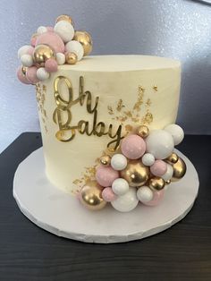 there is a white cake with gold and pink decorations on the top that says baby