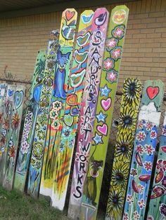 a row of painted wooden boards in front of a brick wall with flowers and hearts on them