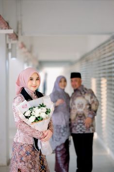 two men and a woman standing next to each other with flowers in their hands,