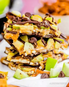 a stack of chocolate and caramel apple slice dessert bars on a white napkin with apples in the background