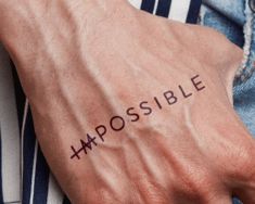 a person's arm with the word impossible tattooed on it