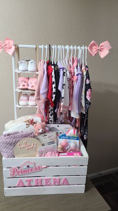 a wooden crate filled with lots of baby clothes and accessories on display next to a wall