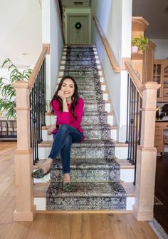 a woman is sitting on the stairs in her home