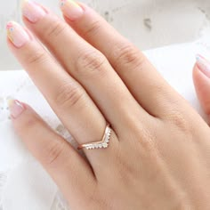 a woman's hand with pink and white manicured nails holding a diamond ring