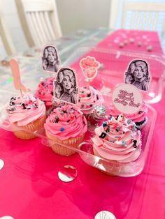 cupcakes with pink frosting and sprinkles are on a table