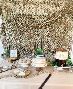 a table topped with cakes and desserts under a netted cloth covered wall behind it