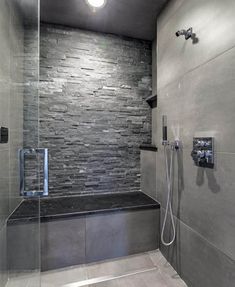 a walk in shower sitting next to a stone wall