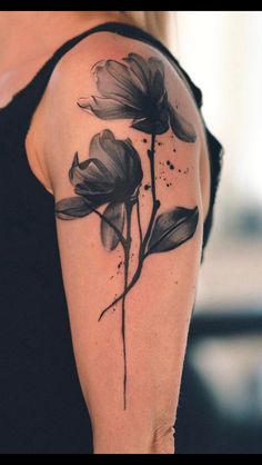 a woman's arm with black ink flowers on the left side of her arm