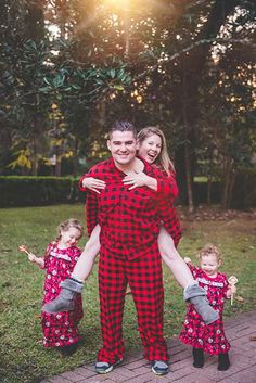 a man and woman in matching pajamas are holding their children while posing for the camera