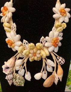 a necklace made out of shells and flowers on a black mannequin neckpiece