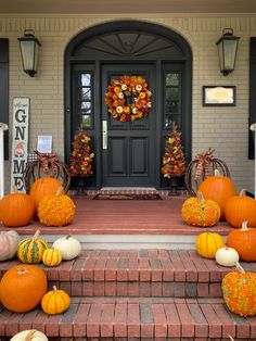 pumpkins and gourds are sitting on the front steps