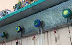 a shelf with several different colored glass beads hanging from it's sides and chains on the bottom