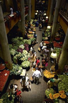 an overhead view of a market with people shopping for fruits and veggies in it