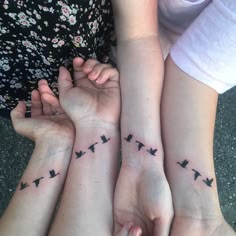 three girls with matching tattoos on their arms and hands are holding each other's hands