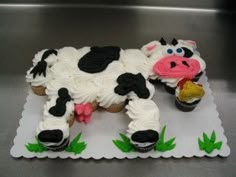 a cake shaped like a cow with cupcakes