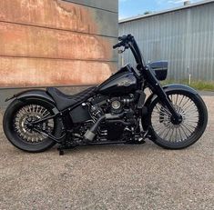 a black motorcycle is parked in front of a building with a large wall behind it