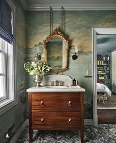 a bathroom with green walls and a wooden vanity topped with a mirror next to a window