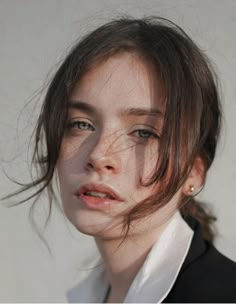 a woman with freckles on her face is looking at the camera while wearing a white shirt and black blazer