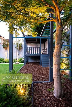 an outdoor play area with stairs and trees in the back yard, surrounded by landscaping