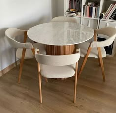 a dining room table with chairs and a book shelf in the corner next to it