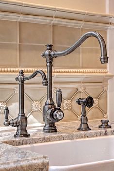 a kitchen sink with two faucets on the side and marble counter tops in front