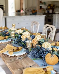 the table is set with blue and white plates, napkins, and pumpkins