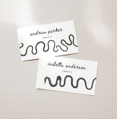 two white business cards with black ink on them, one has a snake and the other has an arrow