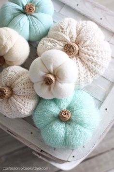 knitted pumpkins are arranged on a white chair with green and blue pom - poms