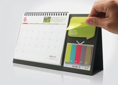 a hand holding a sticky notepad next to a calendar with the words real shop written on it